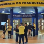 Estande da CVC em evento de franquias, com o espaço “Experiência do Franqueado” e interação com visitantes
