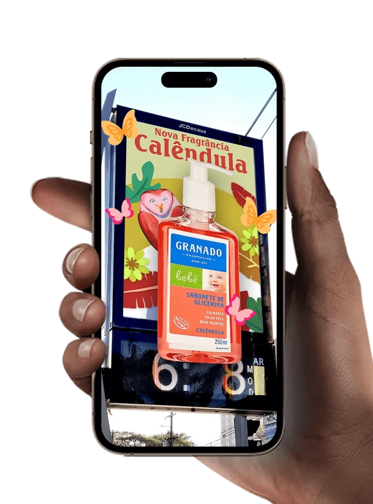 Mão segurando um smartphone exibindo uma ativação interativa de mídia OOH com sabonete Granado Bebê e o anúncio “Nova Fragrância Calêndula” em um painel urbano.