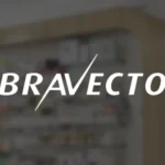 Miniatura de projeto em realidade aumentada (AR) da Bravecto, com logotipo branco centralizado sobre fundo desfocado de farmácia/pet shop.